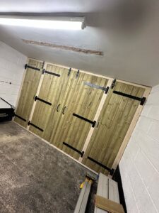Interior view of a garage featuring large wooden sliding doors with black hardware, showcasing a modern design and efficient space utilization.