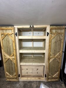 Wooden cabinet with double doors and a central drawer, featuring a rustic design and multiple shelves for storage.